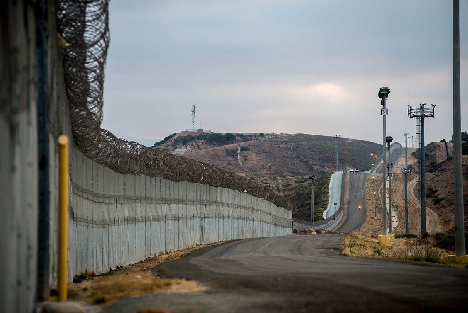 Stretches of secondary fencing are topped with spirals of concertina wire along the U.S.-Mexico border between the San Ysidro and Otay Mesa ports of entry, in San Diego on Aug. 16, 2017. Border Patrol agents use the frontage road between this and primary fencing to patrol for immigrants attempting to enter the U.S. illegally. <em>(Brandon Quester/inewsource)</em>